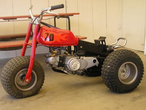 1900 Honda Big Red - This three-wheeled ATV features a red gas tank with flames and the number 70. The Honda logo is visible on the engine.