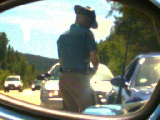 1996 Ford Probe - Man in cowboy hat reflected in side mirror, with traffic on a sunny day.