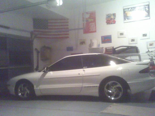 White 1996 Ford Probe parked in a garage with an American flag on the wall