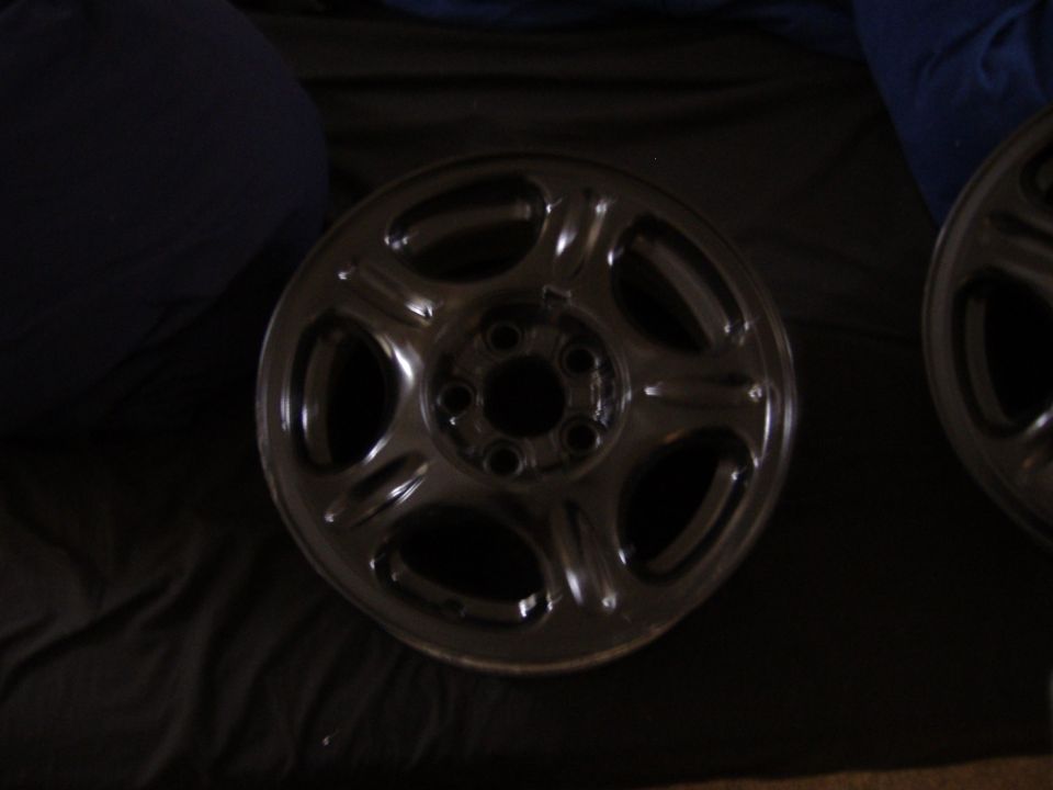 Close-up of a single dark-colored car wheel with five spokes