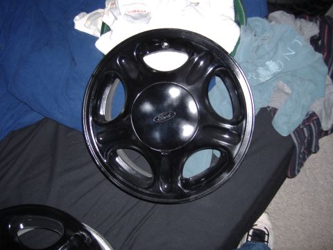 1998 Ford Taurus - A black hubcap with a Ford logo is shown, likely a replacement part.