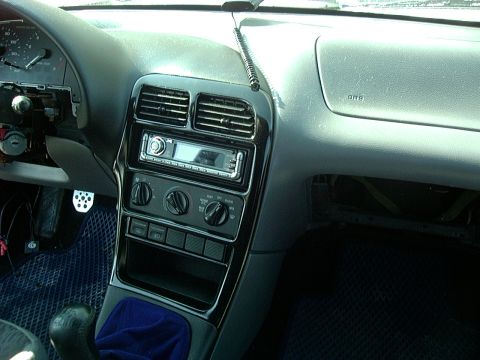 1995 Ford Probe - The interior of a car shows the dashboard with an aftermarket stereo and climate controls, with the instrument cluster partially disassembl…