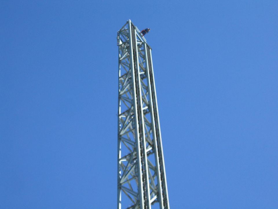 Tall silver lattice tower ride against a clear blue sky