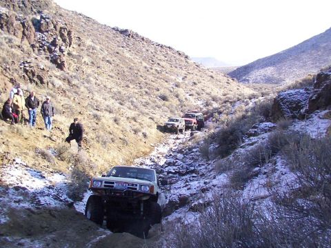 1978 Ford Bronco - A convoy of off-road vehicles navigates a rocky, snow-dusted canyon trail.