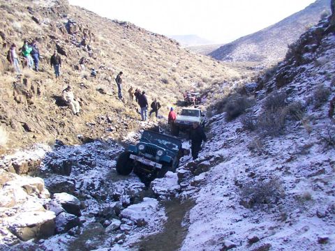 1978 Ford Bronco - A group of off-road vehicles are seen on a snowy, mountainous trail with spectators.