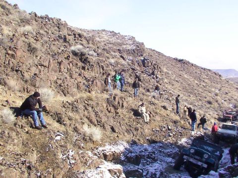 1978 Ford Bronco - A group of people and off-road vehicles are gathered on a steep, rocky incline with patches of snow.