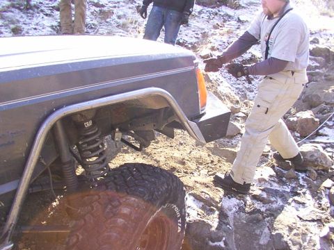 1978 Ford Bronco - A person attempts to free an off-road vehicle stuck on a steep, rocky incline.