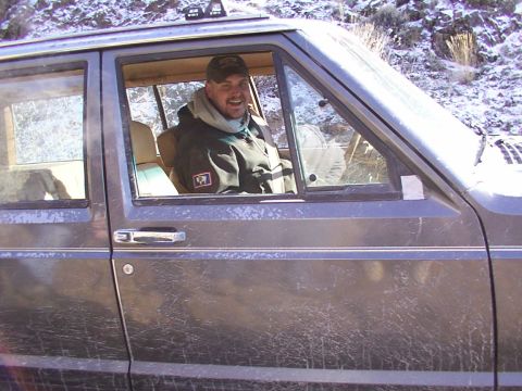 1978 Ford Bronco - A man smiles from inside a Jeep Cherokee, with a snowy, mountainous landscape visible behind him.