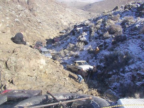 1978 Ford Bronco - Multiple off-road vehicles traverse a challenging, snow-dusted rocky terrain, with one truck requiring assistance.