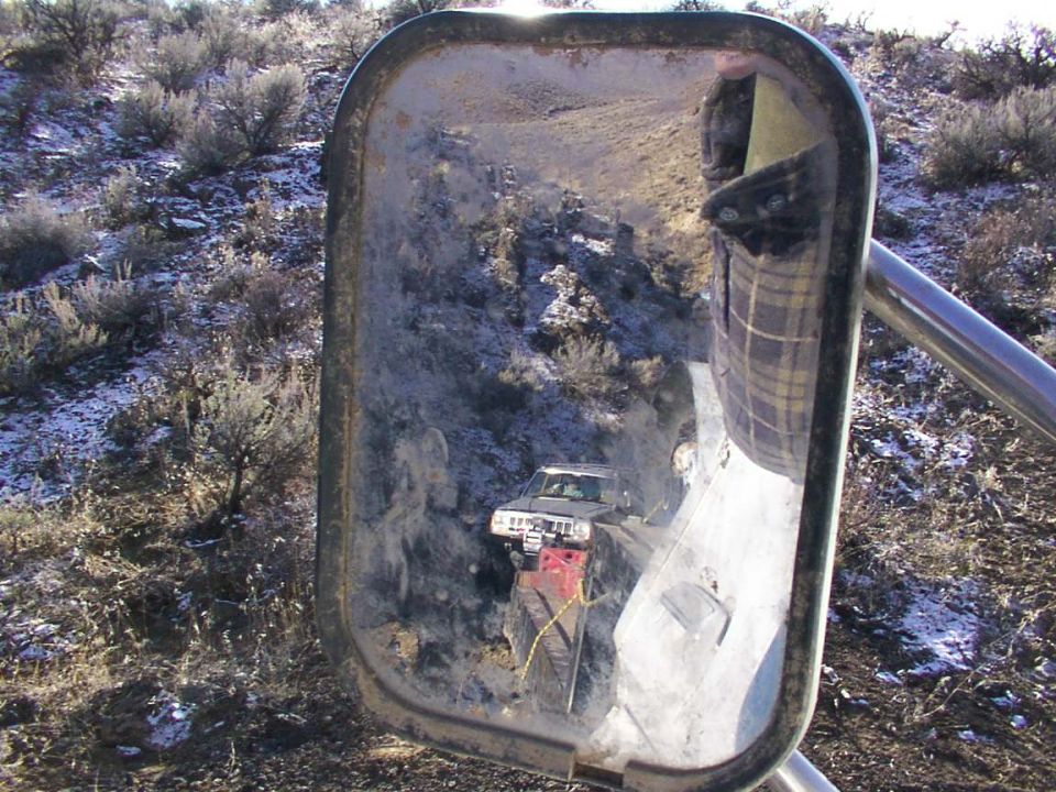 reflection in side mirror shows blurry landscape and sky