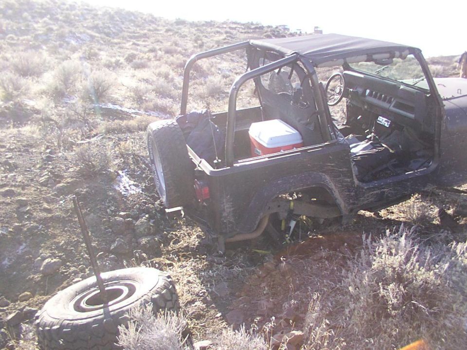 Dark SUV, possibly off-road, with front wheels in mud