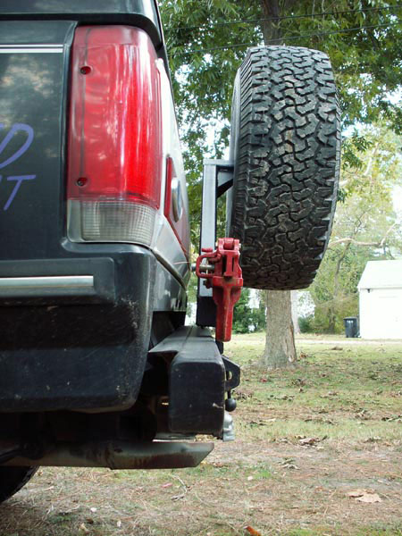 1988 Ford Bronco - Close-up view of a rear bumper and spare tire carrier, a red Hi-Lift jack.