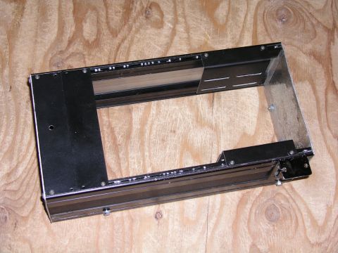 1999 Ford Crown Victoria - Metal console bracket, likely for a vehicle interior, shown against a wood background.