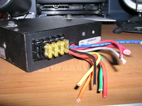 1999 Ford Crown Victoria - A close-up view of an electrical fuse box with several wires connected.