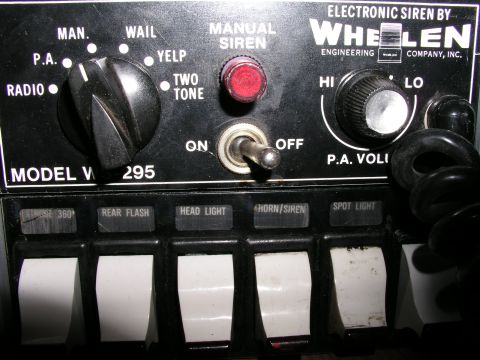 1999 Ford Crown Victoria - Close-up of a Whelen V295 electronic siren control panel, showing various function selectors and switches.