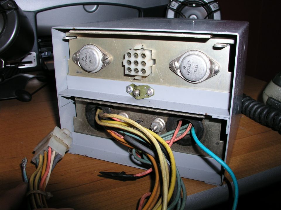 Electronic device with exposed wiring and transistors, showing a multi-pin connector and various colored cables entering a metal casing
