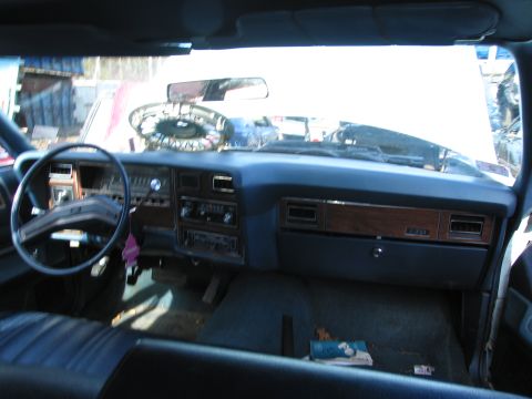 1991 Ford LTD Crown Victoria - Interior of an older car showing a blue dashboard with woodgrain trim, steering wheel, and bench seat.