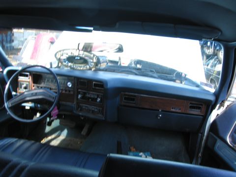 1991 Ford LTD Crown Victoria - View across a car's blue dashboard with woodgrain accents and steering wheel, seen from the back seat through the windshield.
