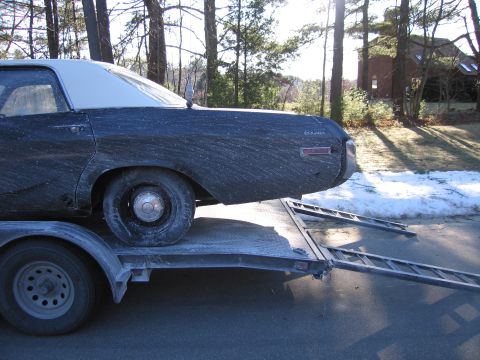 1991 Ford LTD Crown Victoria - dusty dark two-door coupe with a flat tire loaded on a tilt trailer in a driveway with snow on the ground.
