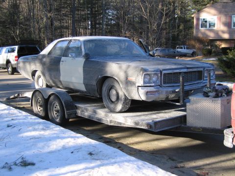 1991 Ford LTD Crown Victoria - dust-coated full-size sedan with a chrome grille and stacked headlights sits on a flatbed trailer in a driveway with patchy snow.