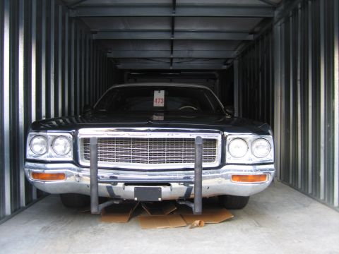 1991 Ford LTD Crown Victoria - black full-size sedan with a wide chrome grille and stacked headlights sits parked inside a corrugated metal shipping container.