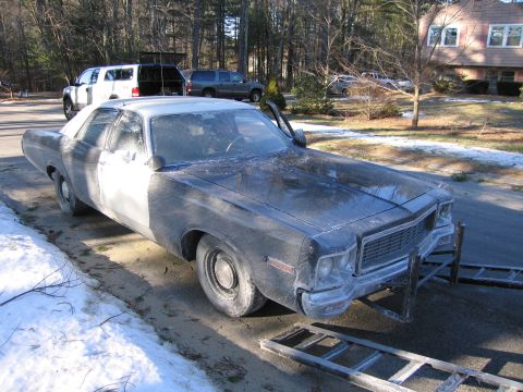 1991 Ford LTD Crown Victoria - grimy dark full-size two-door sedan rests in a driveway by a loading ramp, with an SUV and pickup parked behind it.