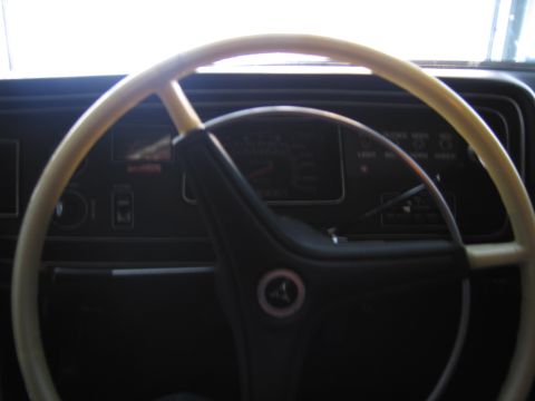 1991 Ford LTD Crown Victoria - Interior view of a cream-colored two-spoke steering wheel with a Pentastar horn button in front of a dark dashboard and gauges.