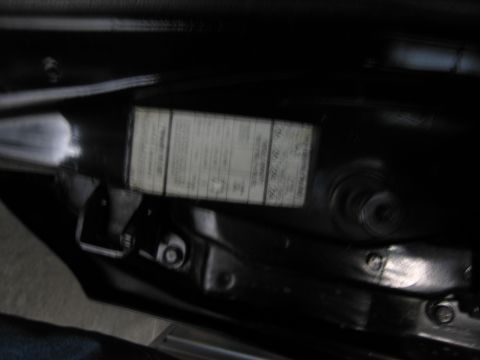 1991 Ford LTD Crown Victoria - dimly lit black door jamb showing a white build or certification data label affixed near sheet-metal seams.