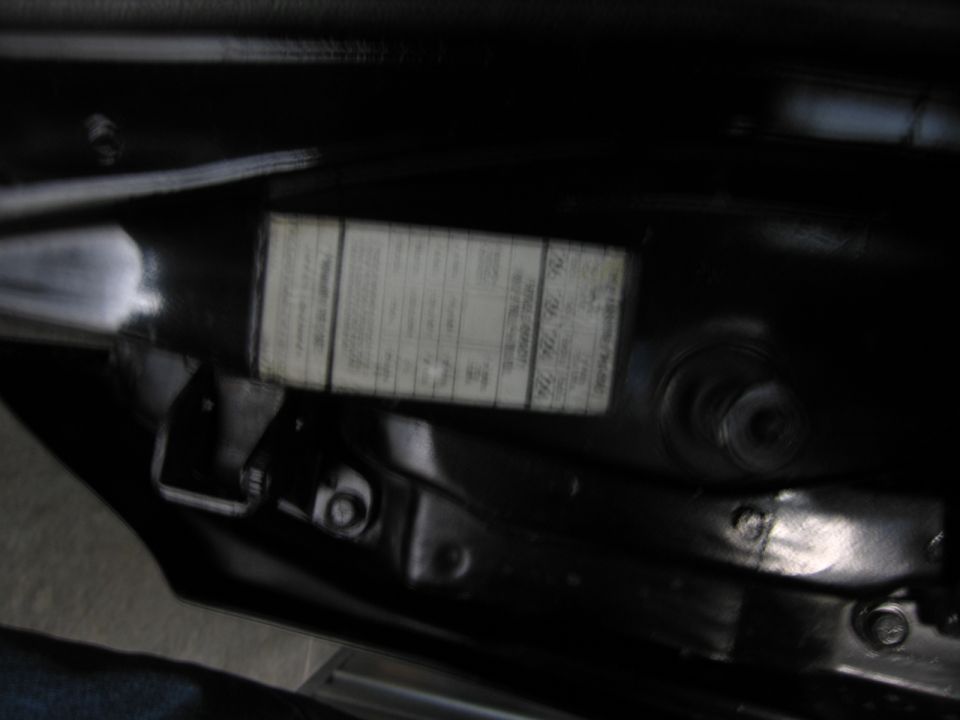 Dimly lit black door jamb with a white build/certification data label