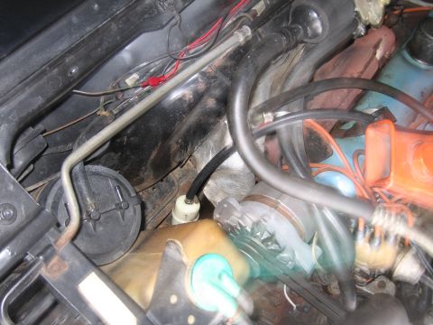 1991 Ford LTD Crown Victoria - engine bay showing an orange-painted component, black rubber hoses, red wiring and a yellowed translucent plastic reservoir.