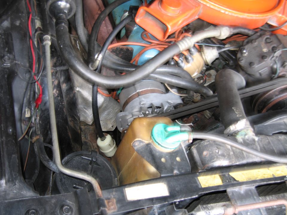 Engine bay detail with orange air cleaner, hoses and brass-colored heat shield