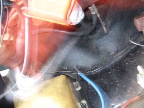 1991 Ford LTD Crown Victoria - blurred, motion-streaked view of an engine bay corner with a blue wire, an orange object and a yellowed plastic reservoir.