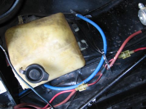 1991 Ford LTD Crown Victoria - top-down view of a yellowed plastic fluid reservoir in an engine bay, surrounded by blue and red wires with inline fuse connectors.