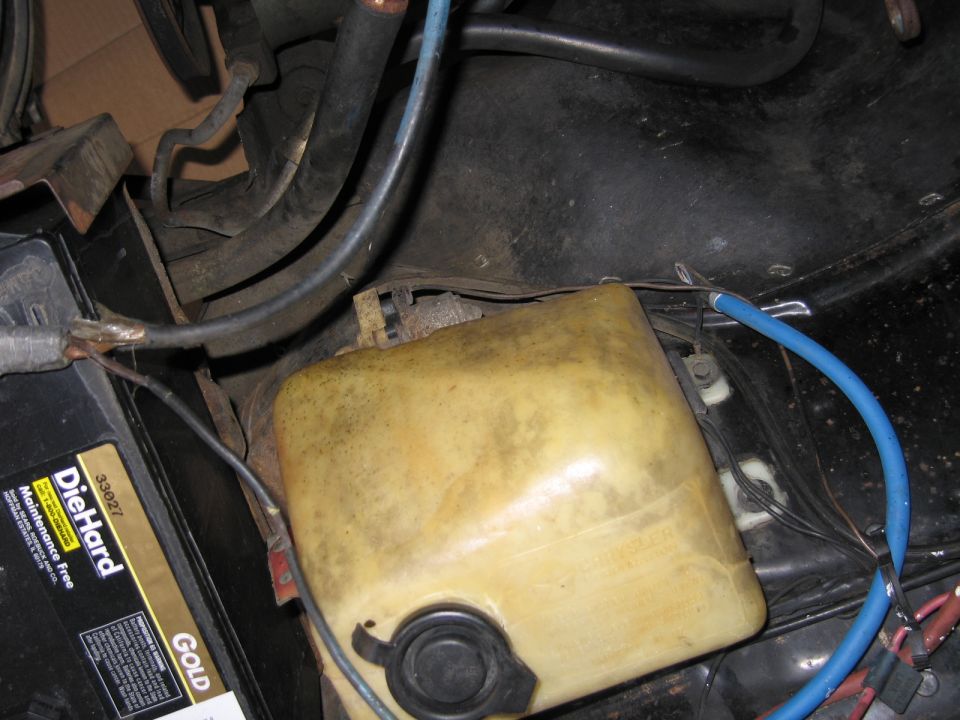 Yellowed plastic reservoir over a DieHard Gold battery with blue and red wires