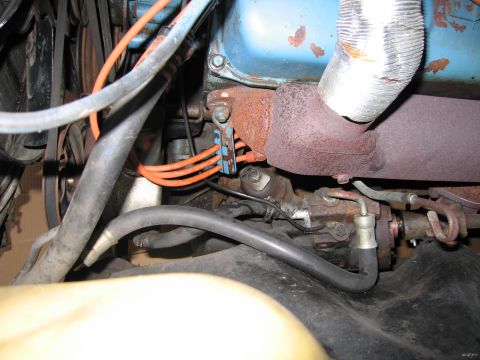 1991 Ford LTD Crown Victoria - detailed engine bay view with a blue engine block, a metal exhaust heat shield, rusty manifold and orange ignition wires.