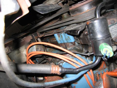 1991 Ford LTD Crown Victoria - engine bay detail showing a black ignition coil with green connector, looping orange spark plug wires and a blue engine block.