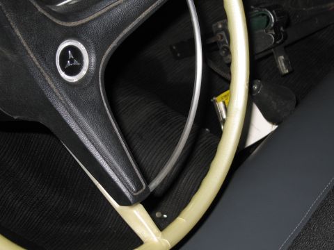 1991 Ford LTD Crown Victoria - vintage car interior detail showing a cream-colored steering wheel and a dash button with a triangular Dodge-style emblem.