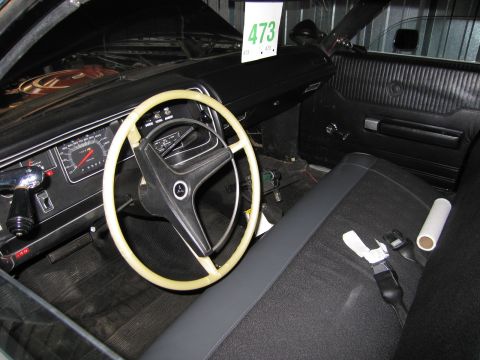 1991 Ford LTD Crown Victoria - interior of a classic car showing a white steering wheel, instrument cluster, bench seat, and a show-entry card numbered 473.