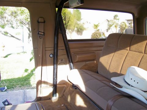 1991 Ford Bronco - Vehicle interior with roll cage and seats, a cowboy hat rests on the passenger seat.