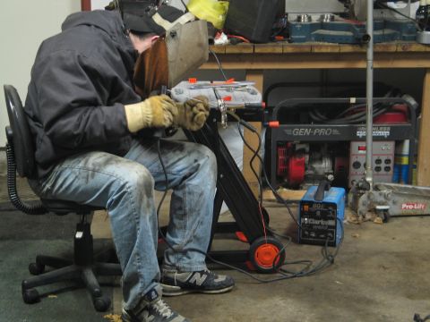1995 Ford Bronco - A person is welding in a workshop setting with a generator and welding equipment present.