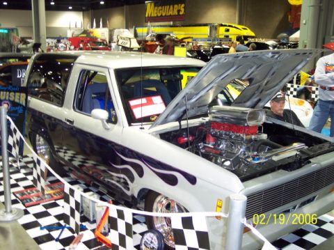 1979 Ford Bronco - A customized SUV with flame decals and a prominent supercharged engine is displayed indoors, dated 02/19/2006.