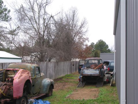 1949 Chevrolet C/K Pickup - Two vintage pickup trucks are parked in a yard, one being loaded onto a trailer.