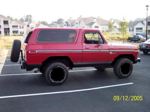 1979 Ford Bronco - Side view of a red 1978 Ford Bronco, parked in a lot with apartment buildings in the background.