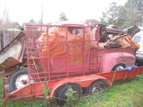 1952 Ford Pickup - A vintage red pickup truck, possibly a 1948 model, is being transported on a trailer, trailer.