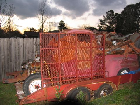 1952 Ford Pickup - A red 1952 Ford Pickup truck bed is visible on a trailer, loaded with debris.