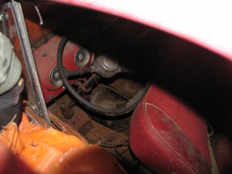 1952 Ford Pickup - The interior of an old vehicle shows a steering wheel, instrument cluster, and red upholstery, suggesting a classic car.