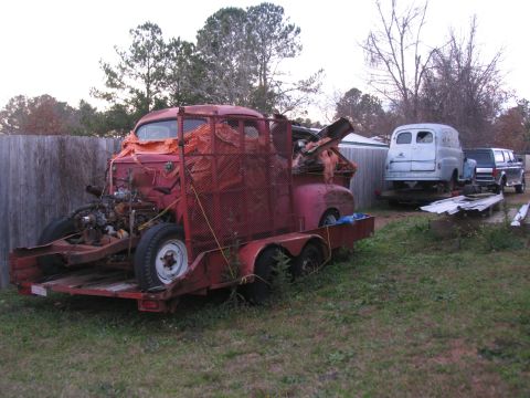 1952 Ford Pickup - A red 1952 Ford Pickup truck is seen on a trailer, with its engine compartment open and covered in orange netting.