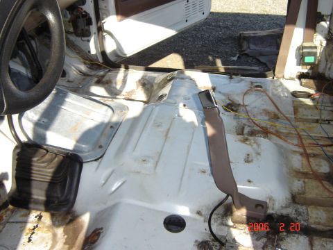1993 Ford Bronco - The interior of a vehicle is shown with the floor stripped down to bare metal, revealing rust and wiring.