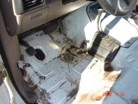 1993 Ford Bronco - Interior floor of a 1993 Ford Bronco showing signs of rust and dirt.