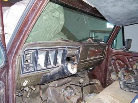 1979 Ford Bronco - The interior of a vintage truck shows a worn dashboard with missing components and a dusty steering column.